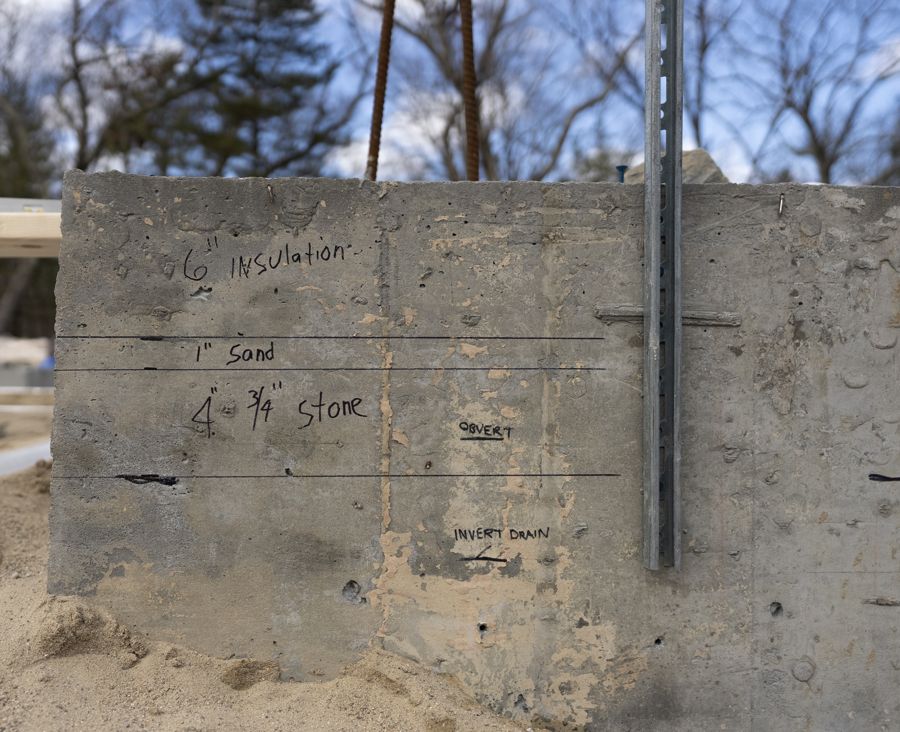 Layer depths marked on the formwork: insulation, sand, stone.