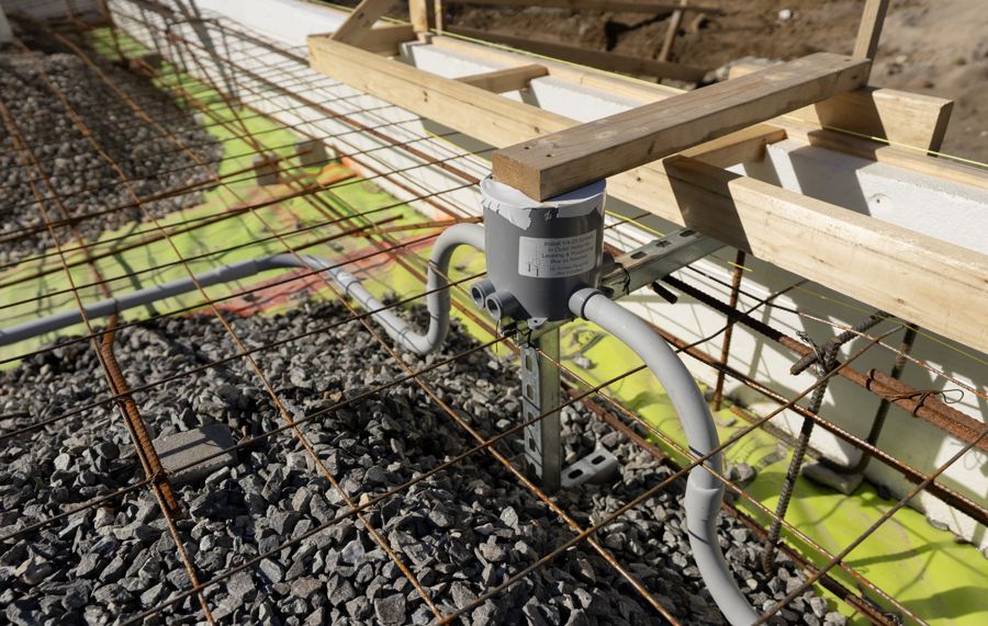 Reinforcing steel over crushed stone, with a conduit box set to height.