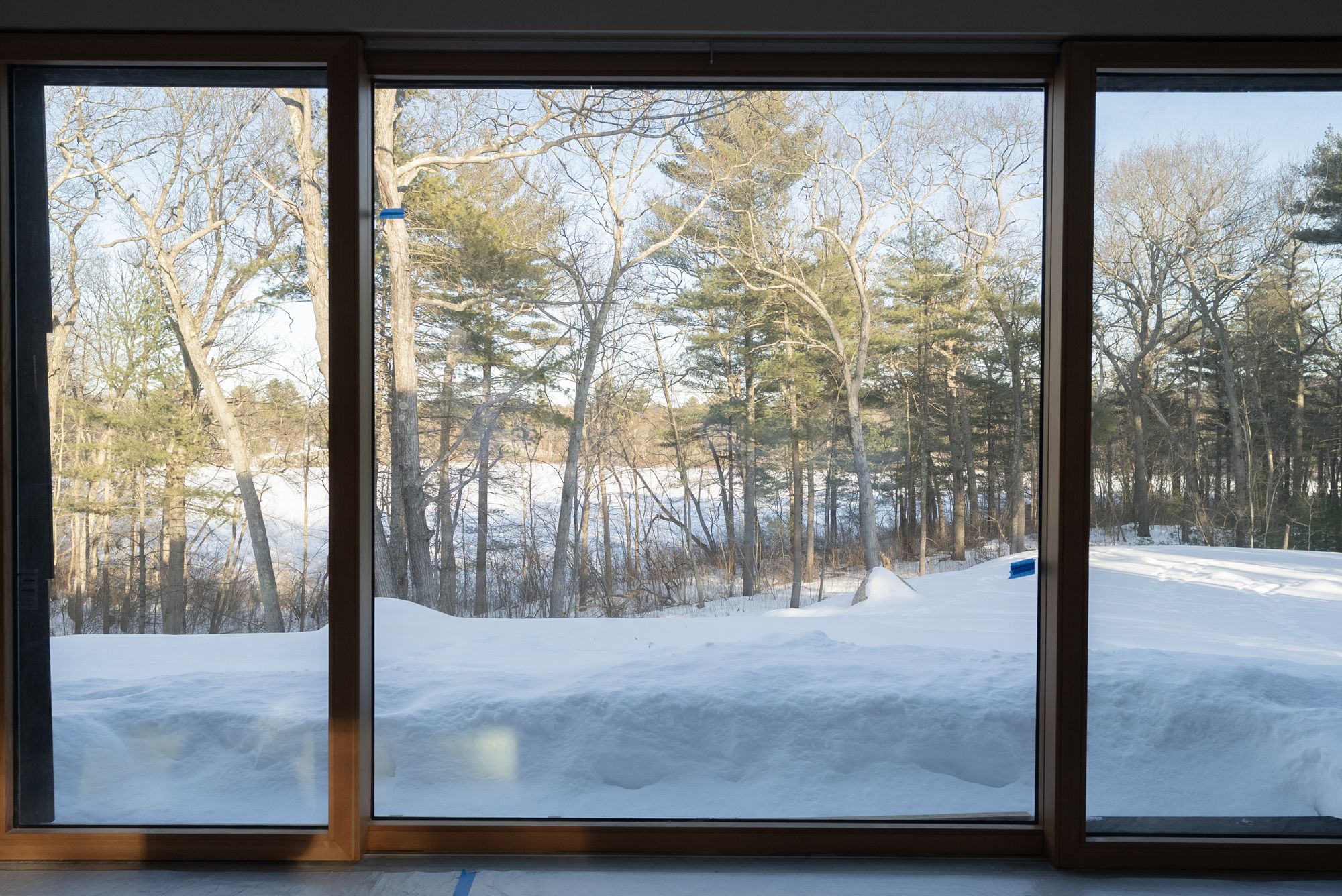 The winter woods and pond seen through the long first-floor glass