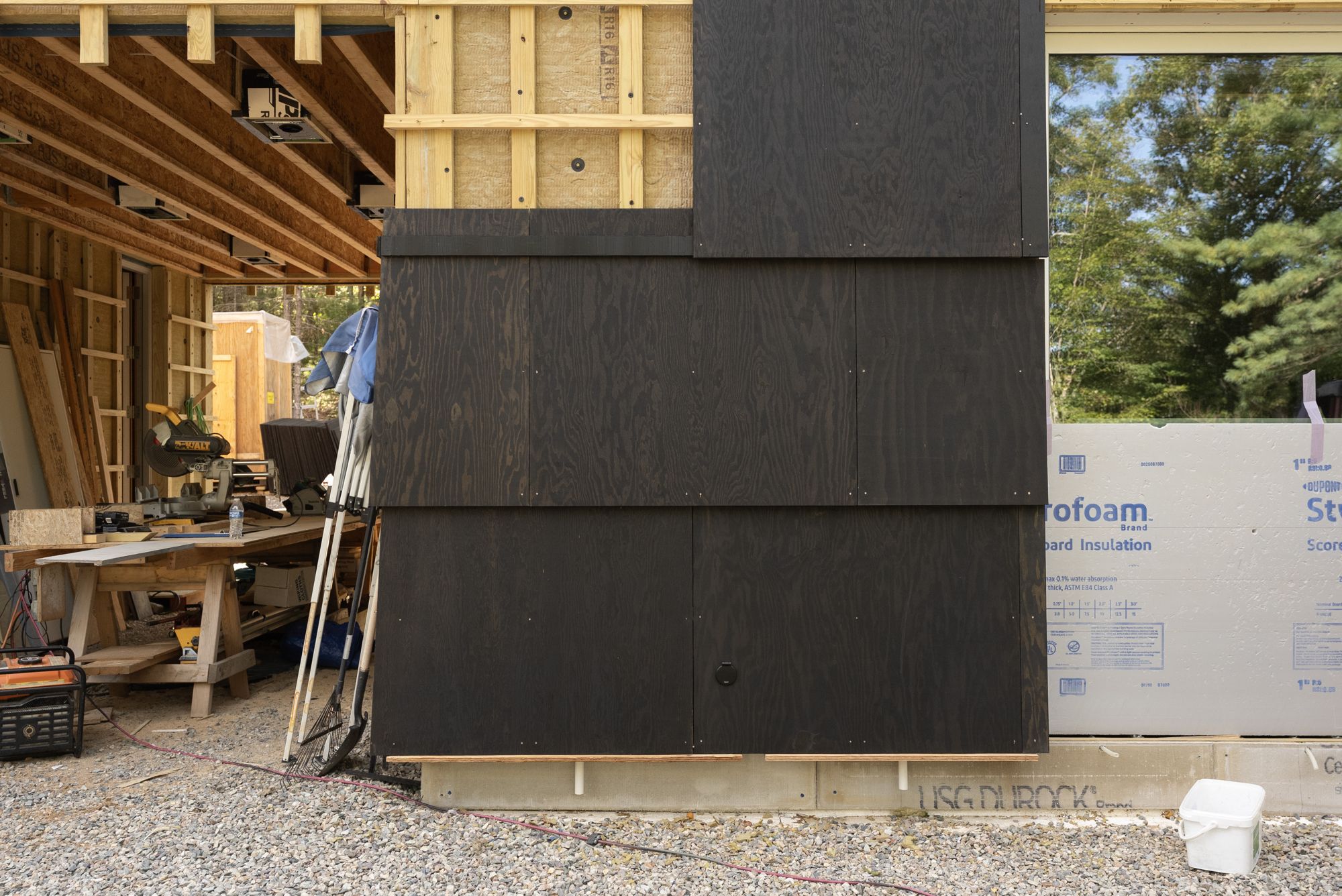 The partly installed field of black shingles on the gable end